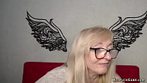 Blonde amateur MILF with glasses IngritSno in grey sweater sitting at the keyboard and chatting with members of her solo webcam show